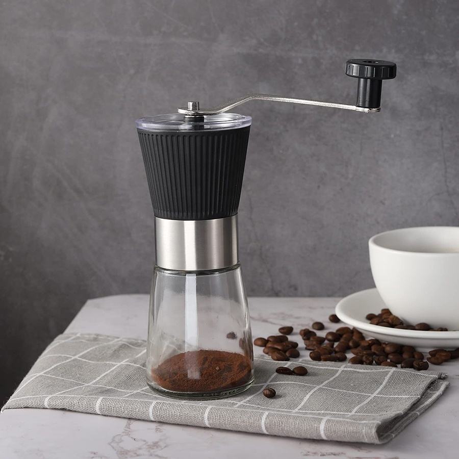 Zwarte handmatige koffiemolen met glazen opvangbeker en koffiebonen